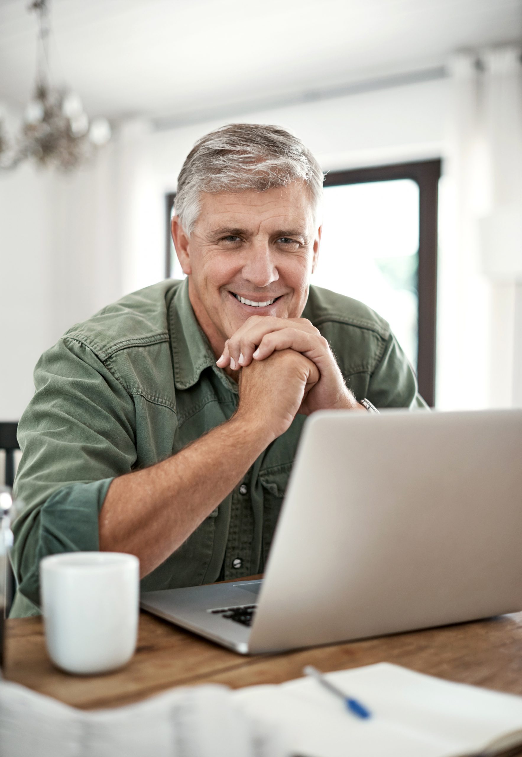 A man sits at a laptop and smiles. The Troutman & Troutman disability lawyers help people in Oklahoma secure financial benefits.