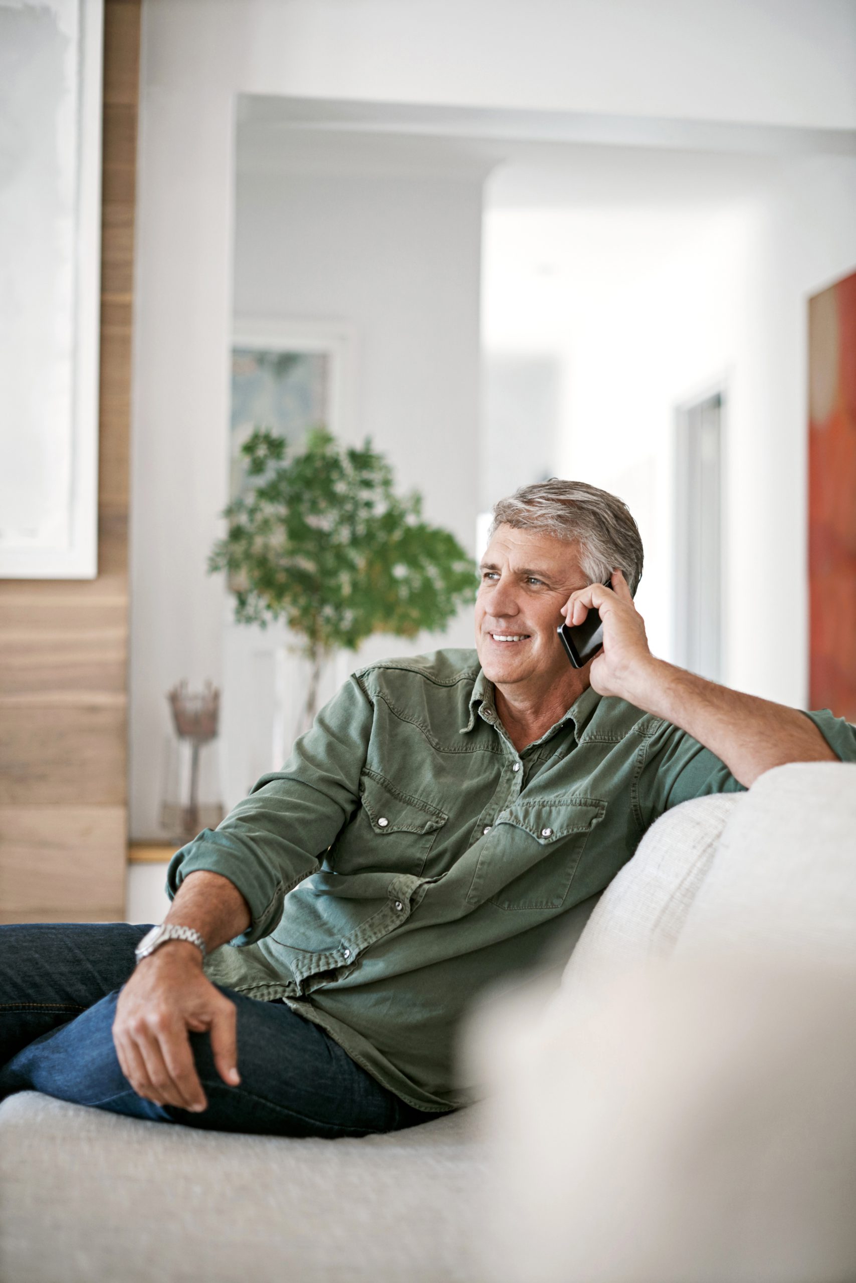 A man sits on his couch, talking on his cell phone and smiling. Social Security Disability lawyers from Troutman & Troutman work closely with you.