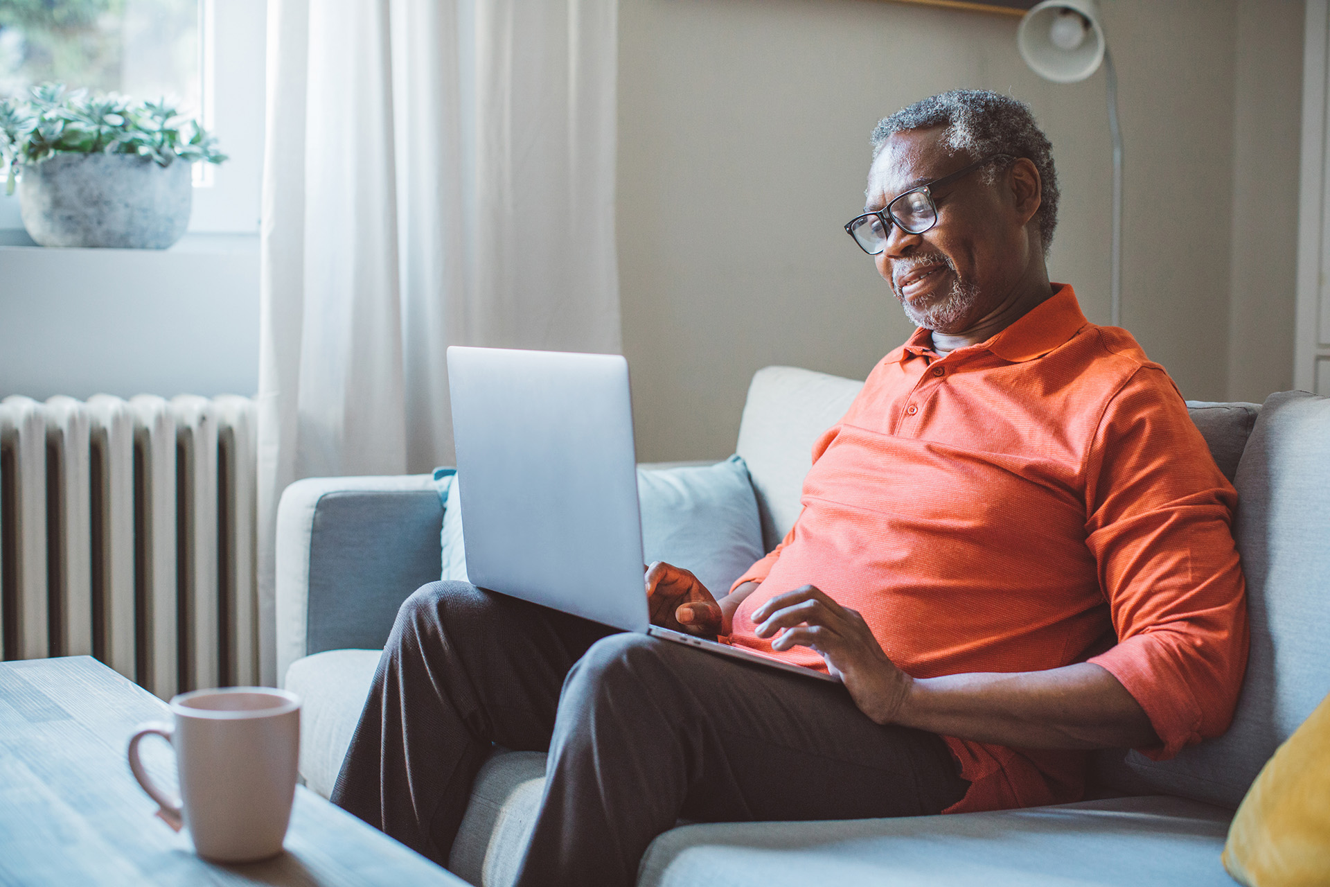 A man smiles as he sits on his couch and reads on his laptop. The Oklahoma disability lawyers at Troutman & Troutman explain how disability claims work on their Social Security Disability blog.