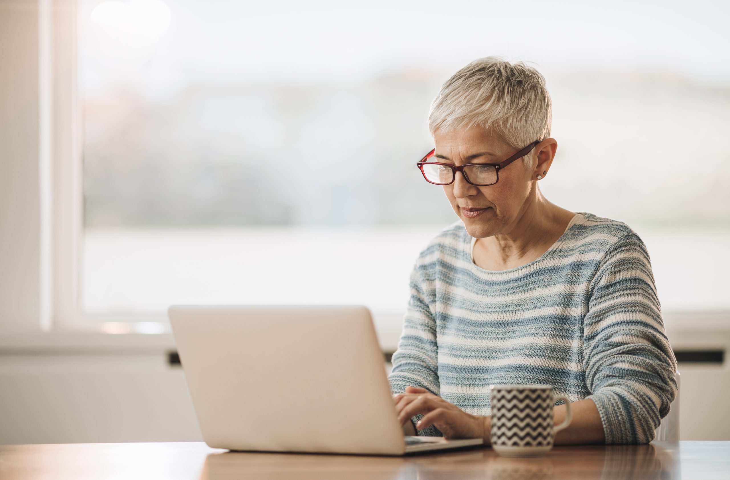 A woman sits at a table typing on her laptop. You can start discussing your disability benefits claim with Troutman & Troutman by getting a free case evaluation.