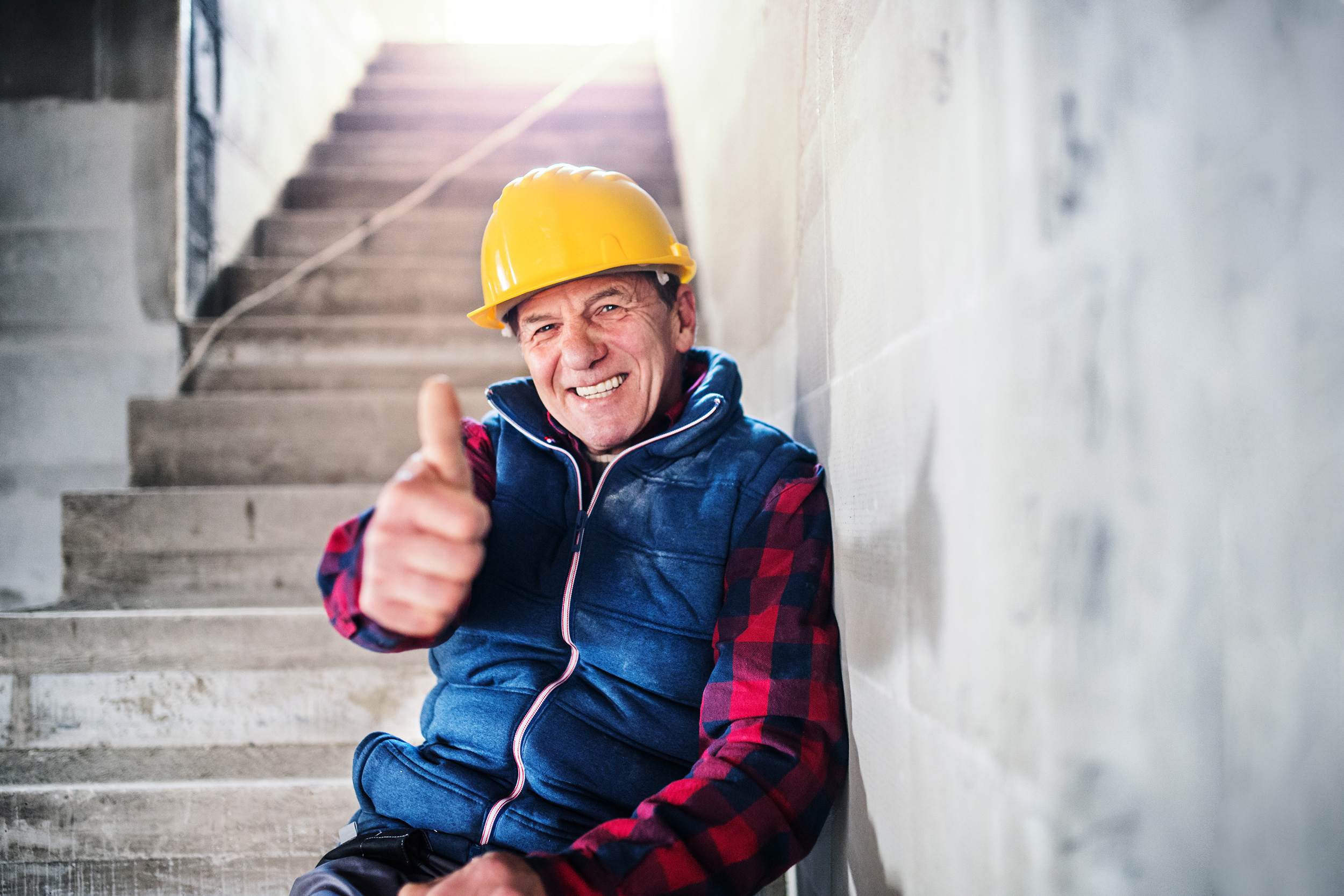 Sitting on concrete stairs, a man in a construction helmet gives a thumbs up. Social Security uses a five-step process to evaluate disability claims.