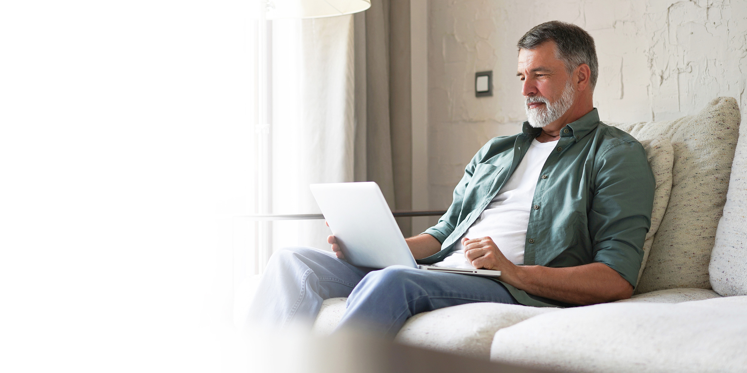 Reclining on his couch, a man looks at his laptop. Troutman & Troutman disability lawyers can explain how to apply for Social Security Disability benefits.