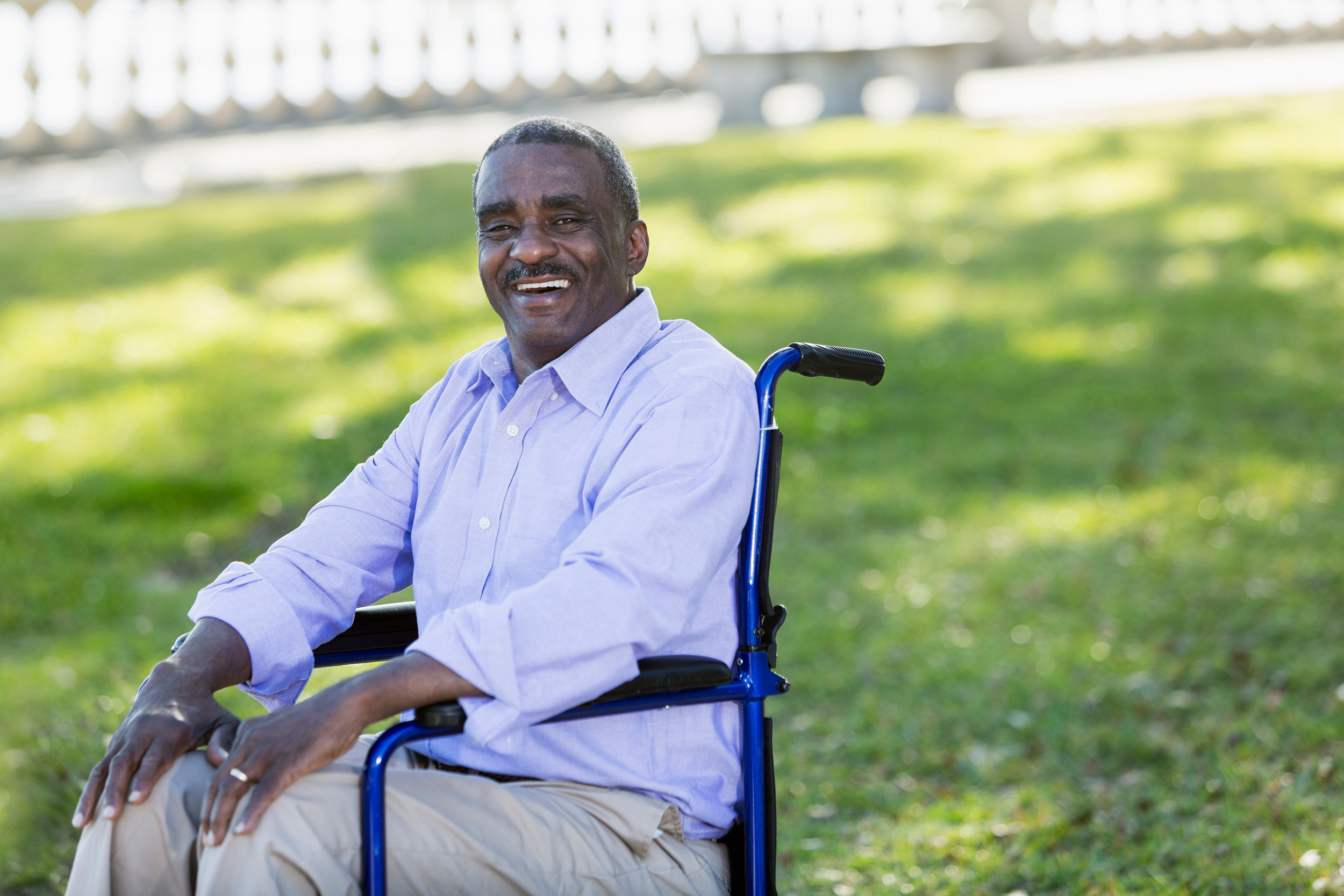 A man smiles as he sits in his wheelchair in a park. Supplemental Security Income (SSI) provides disability benefits for people with limited financial means.