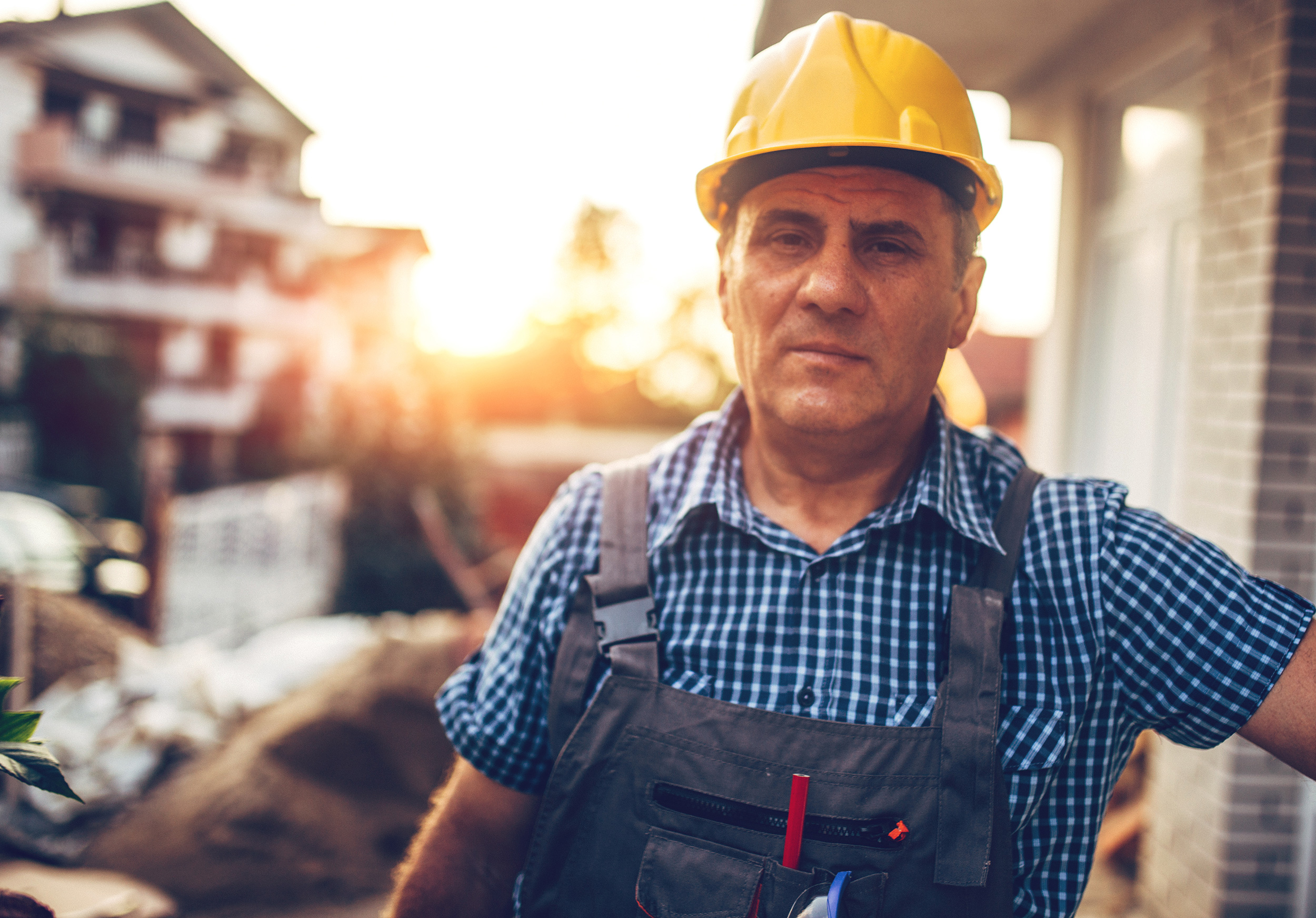 A man in overalls and a hard hat stands in a building construction site at sunset. Social Security uses a five-step process to evaluate disability claims.