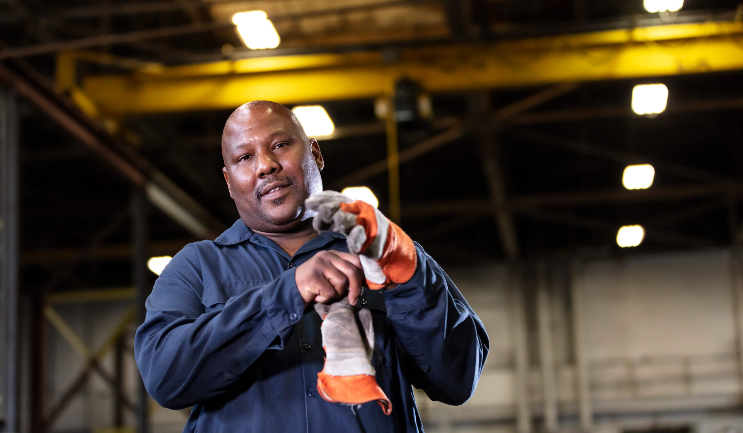 Under warehouse lights, a man puts on his work gloves. Certain limited options allow you to keep working while qualifying for Social Security Disability benefits.