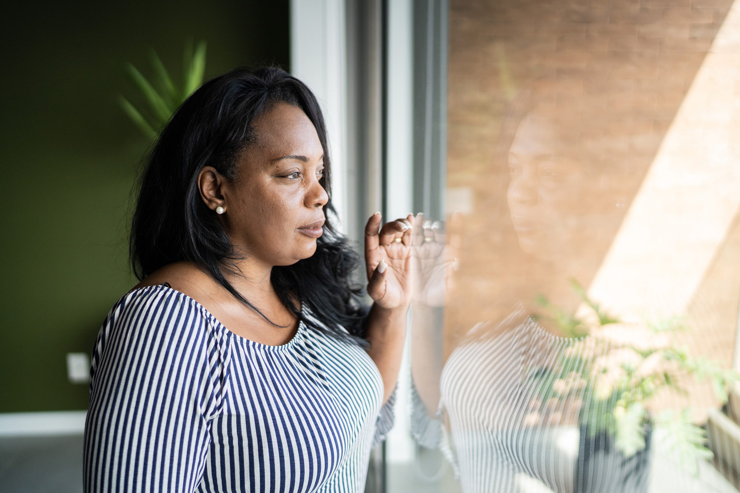 A woman stands at a window looking out. Certain steps can help you avoid losing your eligibility for Social Security Disability.