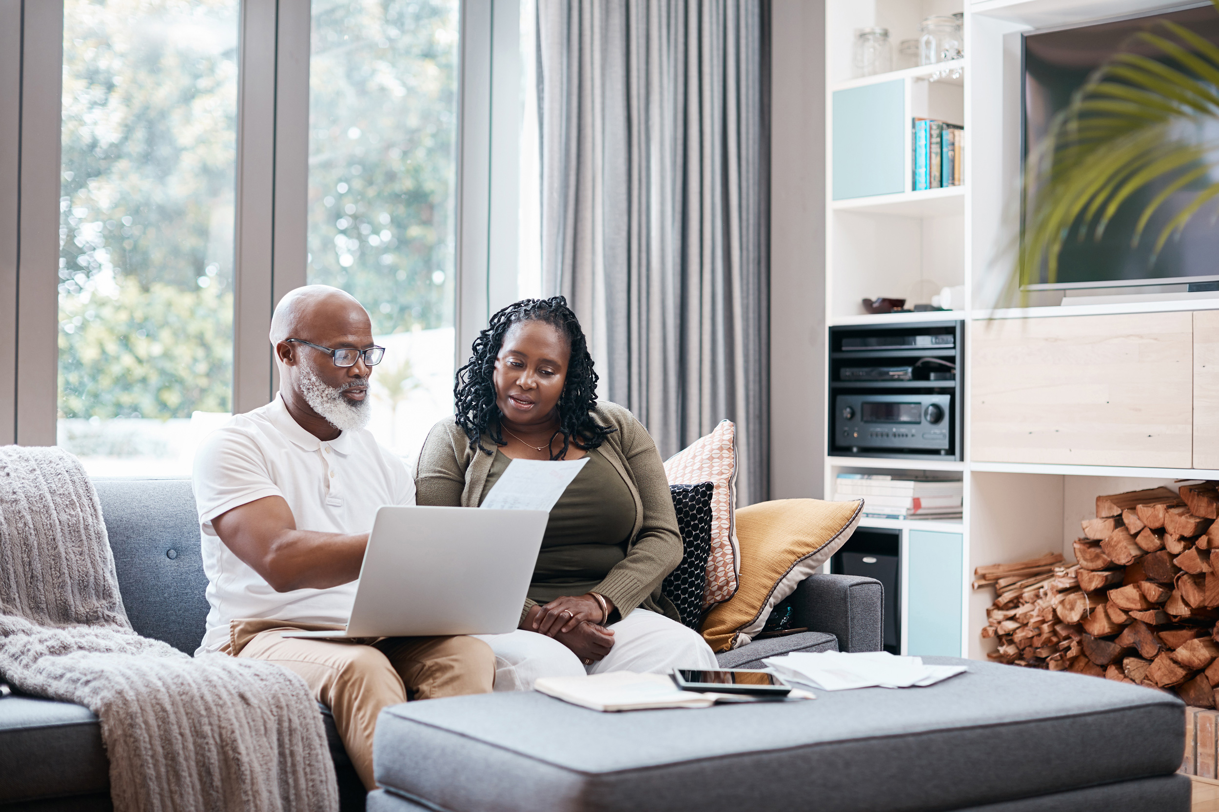 Sitting on a living room couch with a laptop and a tablet computer on the ottoman, a woman and man look over paperwork. Part of the test for getting Social Security Disability benefits is proving you couldn't do other kinds of work from your past experience.