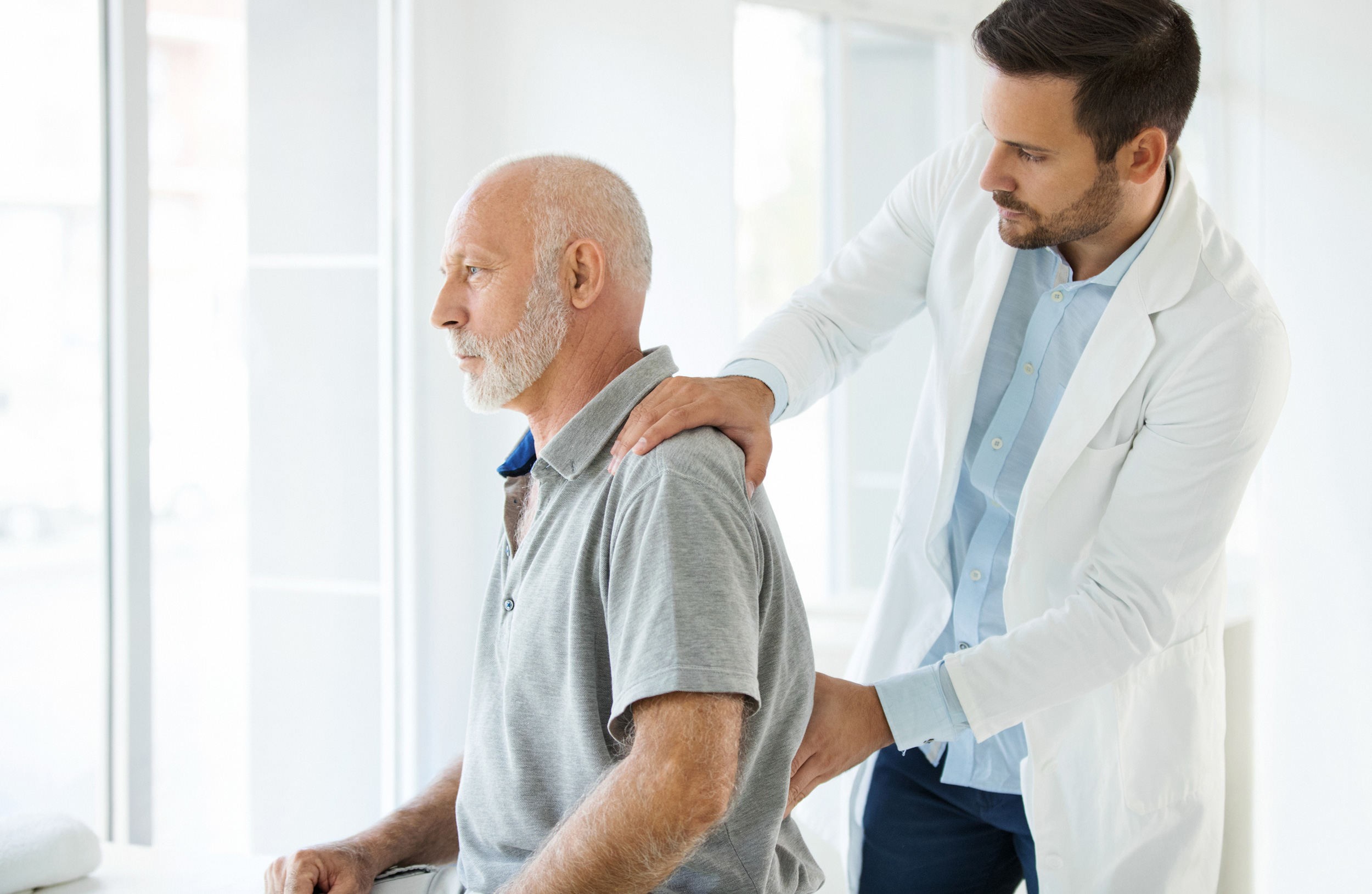 A doctor examines a man by holding his shoulder and pressing on his back with the other hand. The Oklahoma disability attorneys at Troutman & Troutman often see people with conditions like back pain, joint problems, arthritis and more getting approved for disability benefits.