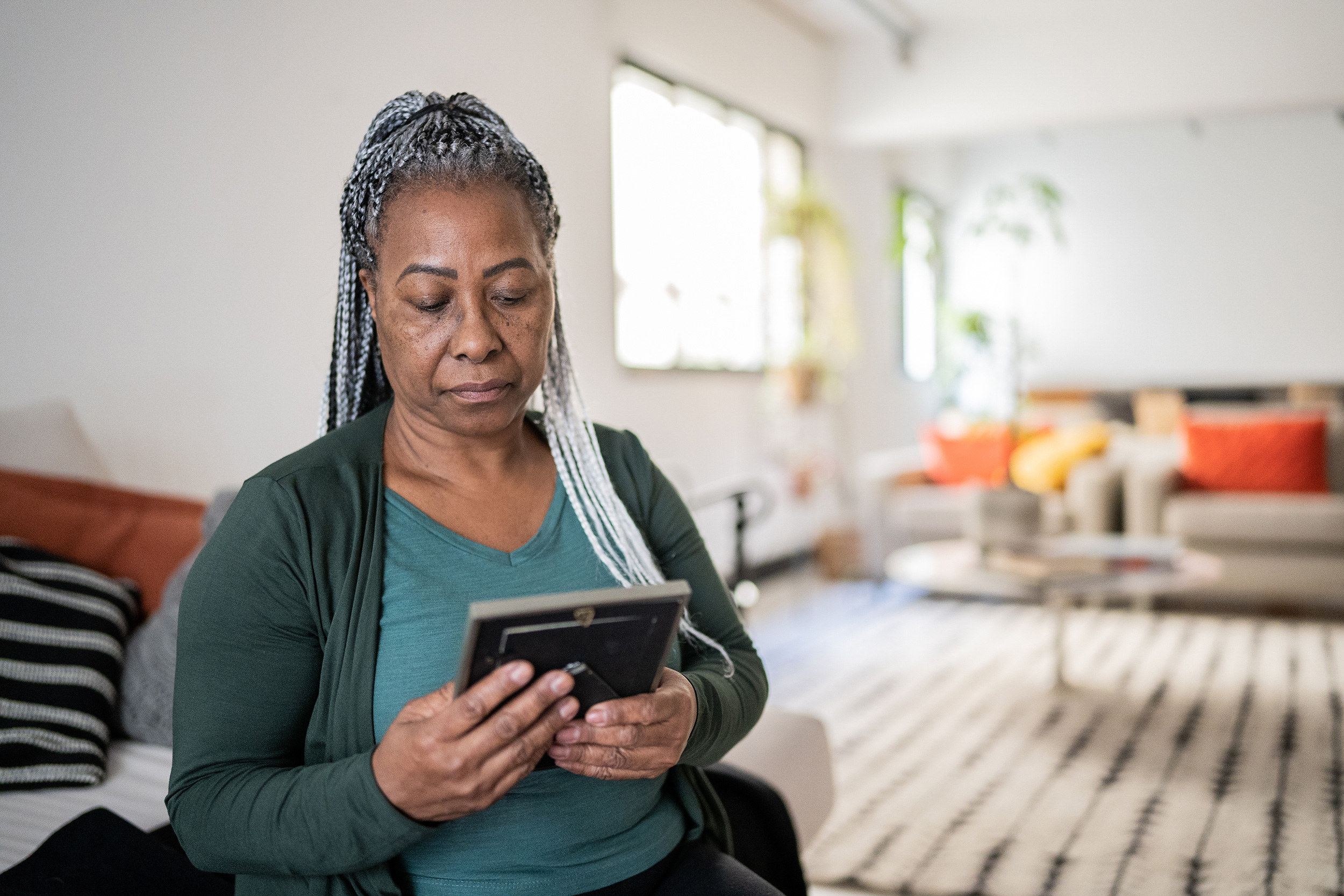A woman holds a picture frame and looks down at it. Death benefits for family members of Social Security Disability recipients can range from 71.5% to full benefits.