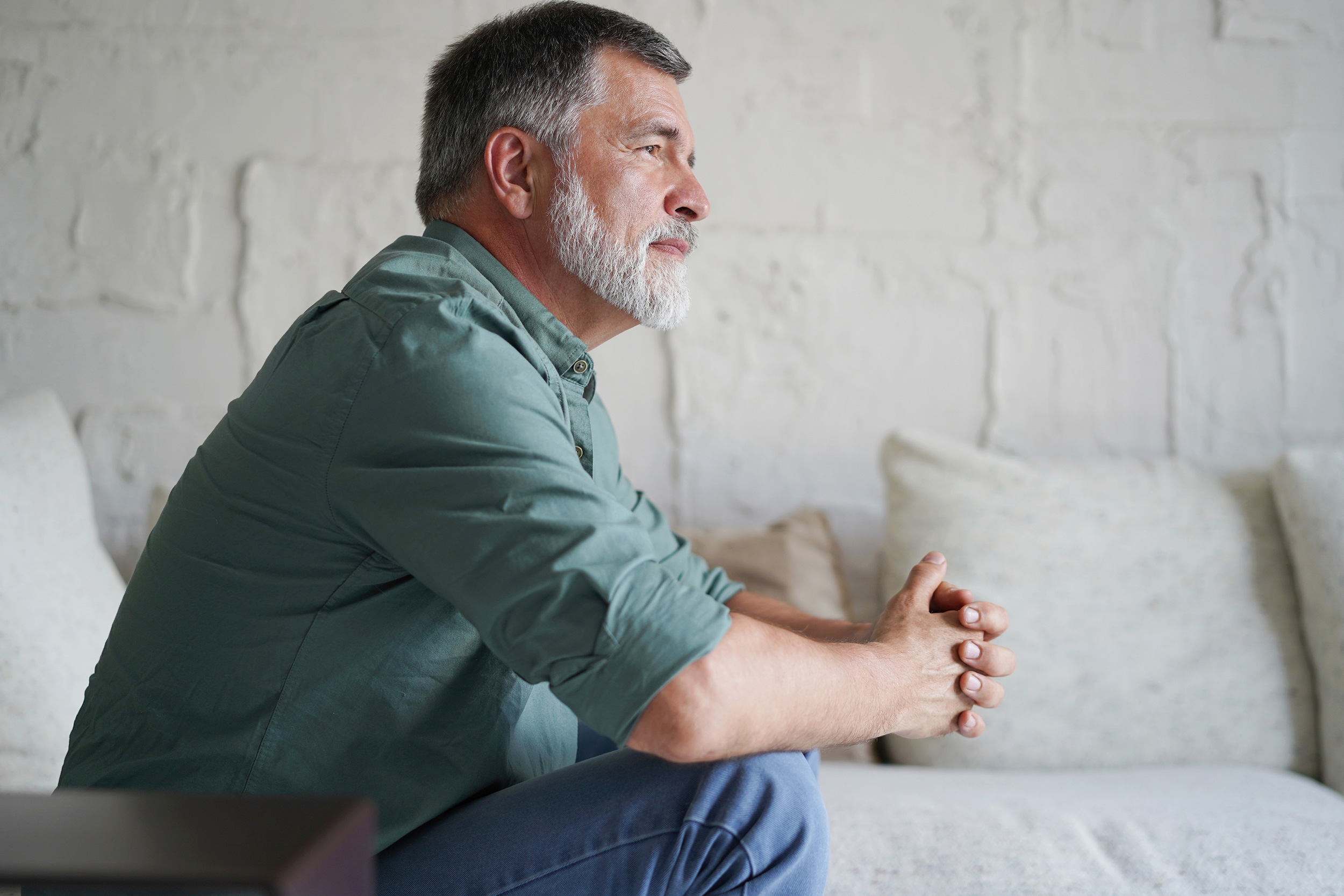 Leaning forward with his hands clasped and elbows on his knees, a man looks on in thought. People often make avoidable mistakes when they apply for Social Security Disability.