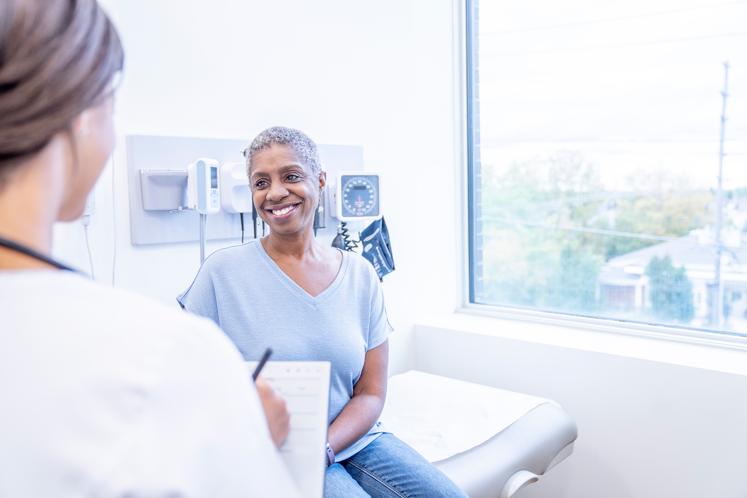 Sitting on an examining table, a patient smiles at her doctor. You can fight a denial of back pay from Social Security Disability benefits, but be careful.