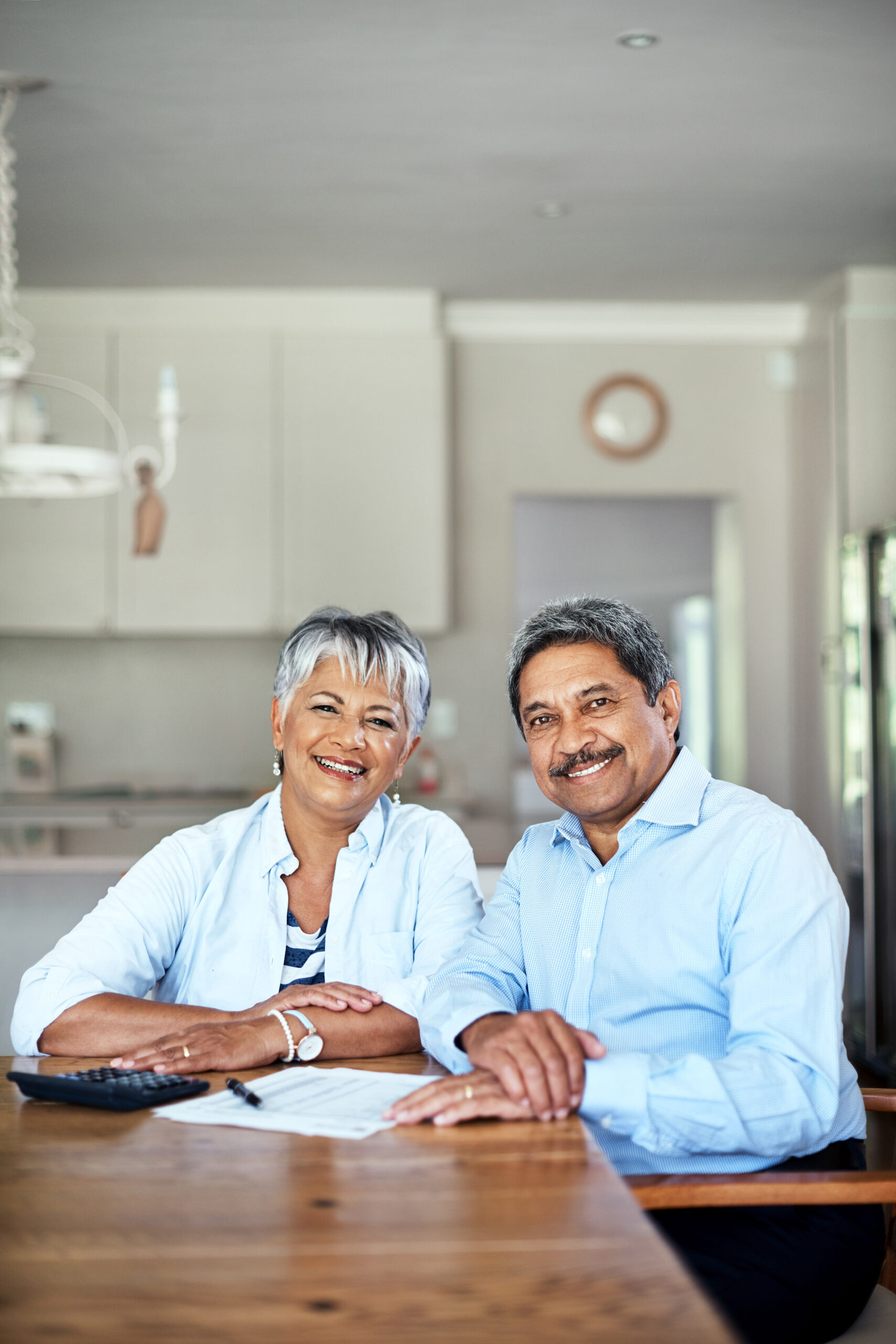 A woman and man sit at a kitchen table smiling for a photo. If you have a Muskogee Social Security attorney from Troutman & Troutman, they can make the process of applying for disability benefits much easier.