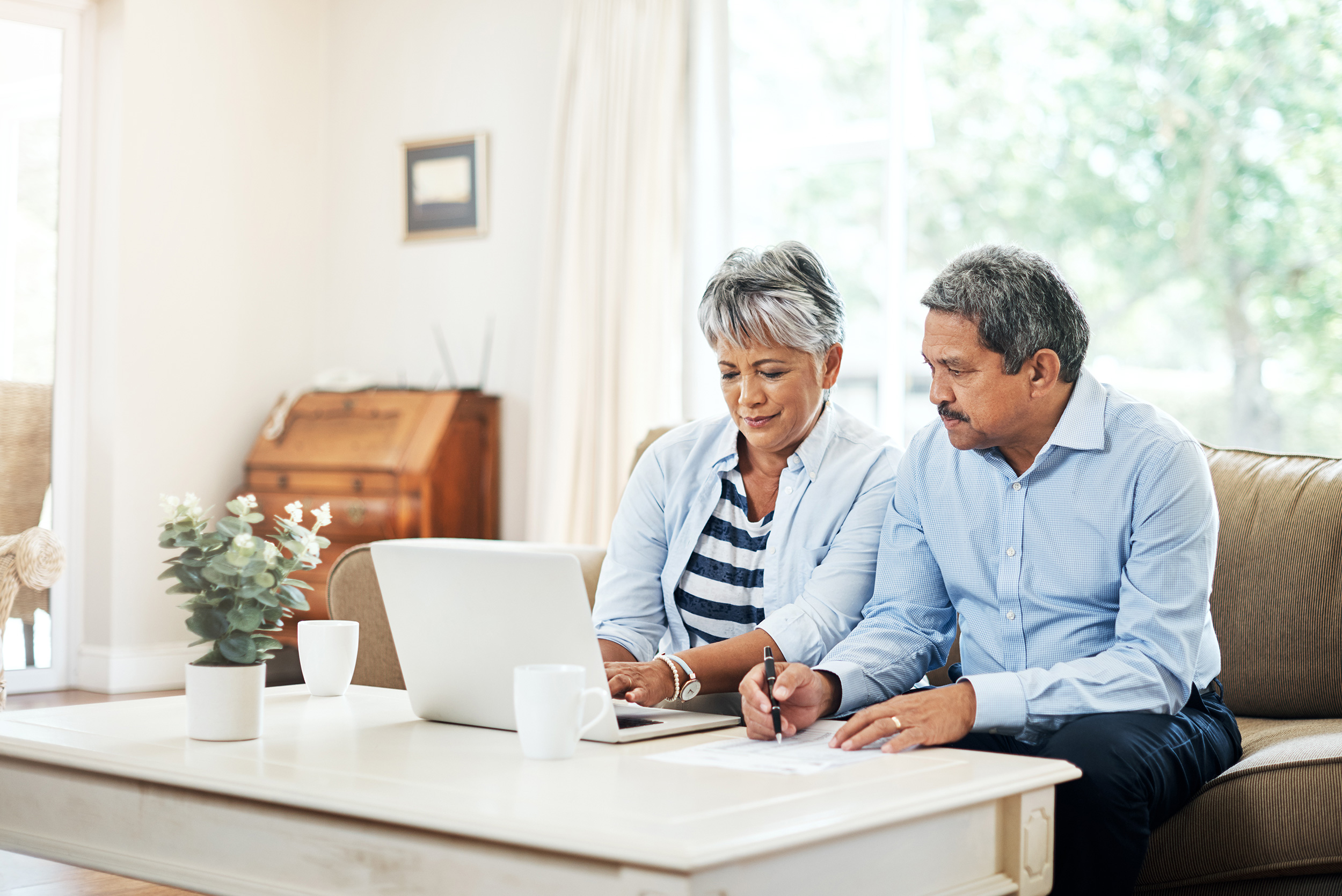 A woman and man sit on their couch looking at a laptop on the coffee table. Troutman & Troutman disability lawyers answer questions about disability benefits every day.