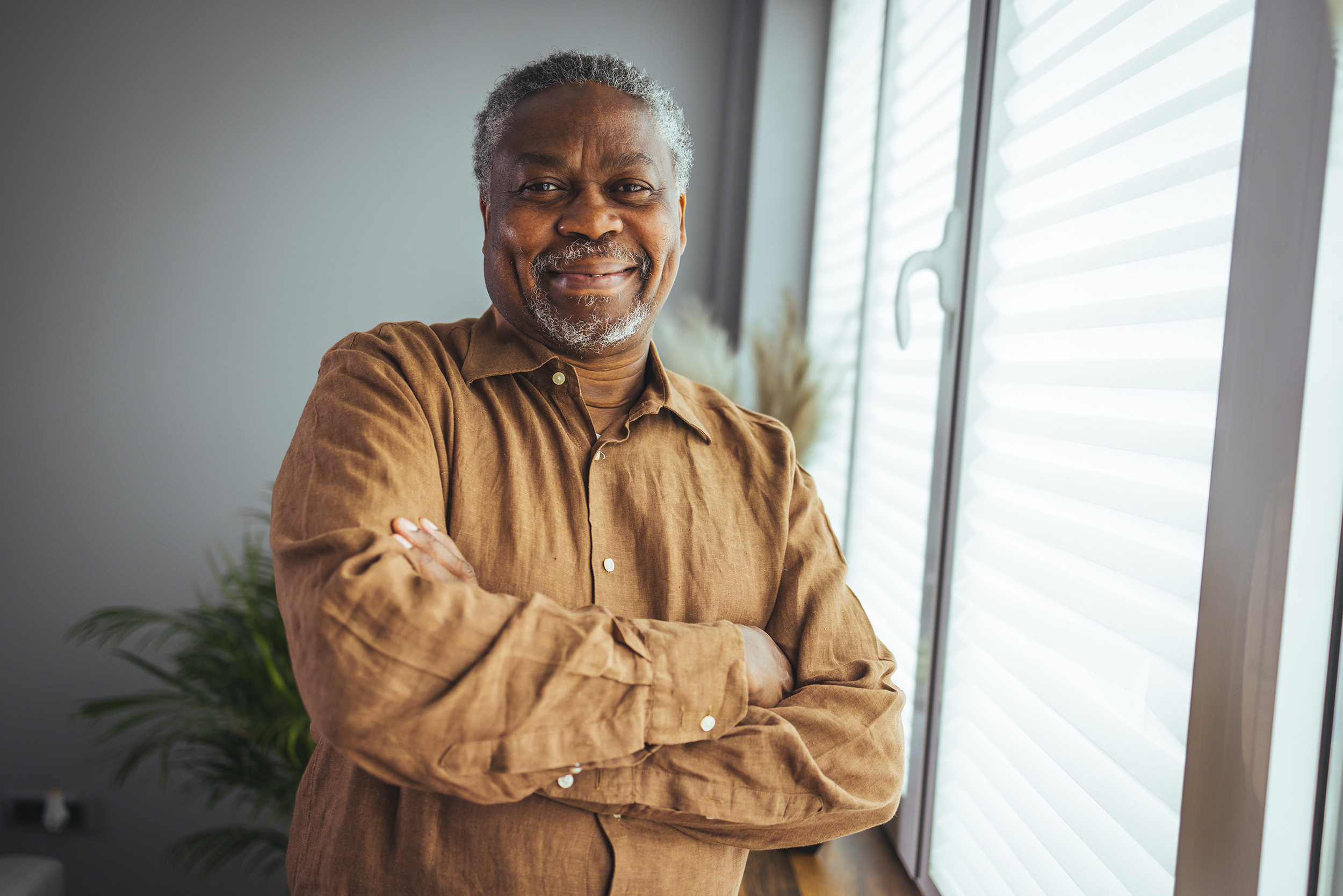 Standing by a window, a man folds his arms and smiles. Troutman & Troutman's Oklahoma disability lawyers answer questions about disability benefits every day.