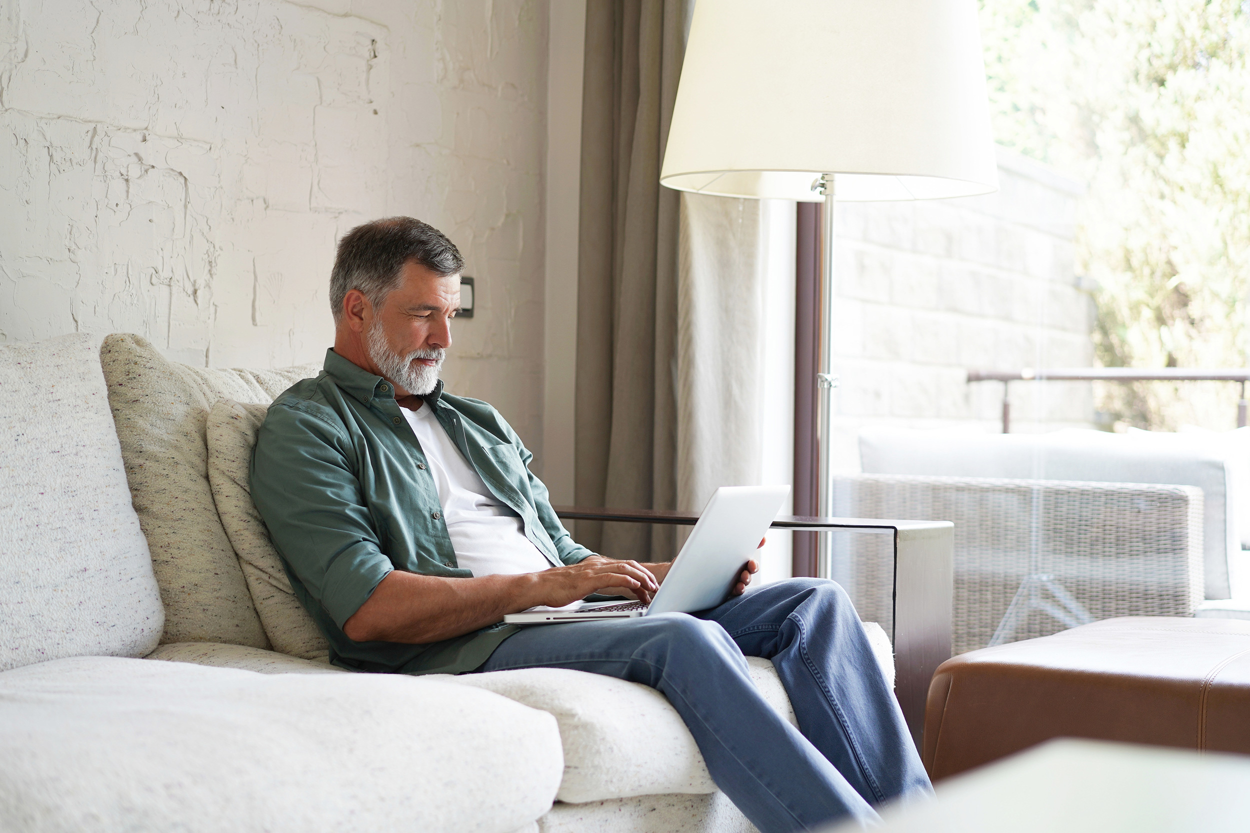 Reclining on his couch, a man types on his laptop. Troutman & Troutman disability lawyers answer questions about disability benefits every day.