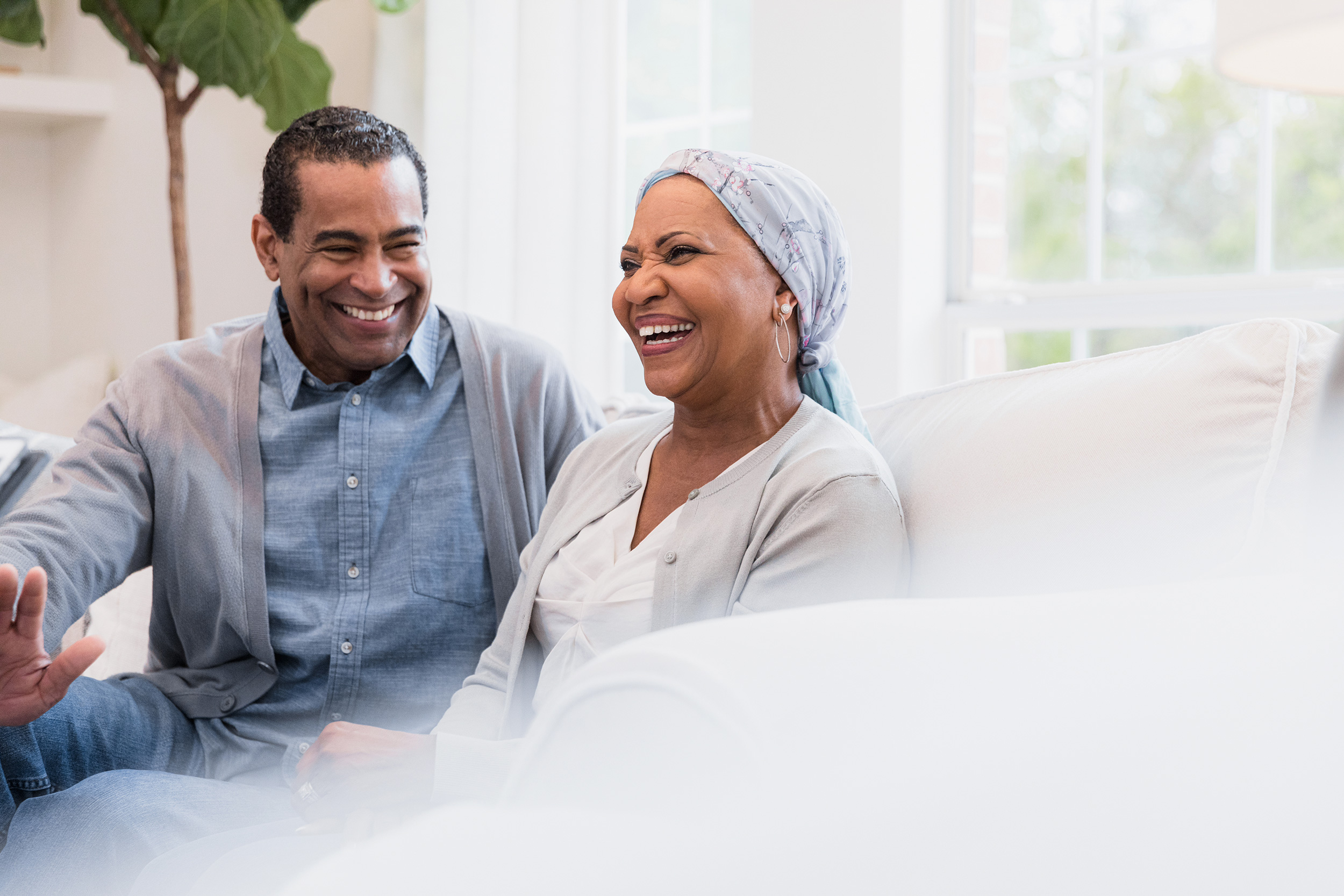 A man and woman it on a couch smiling in conversation. Troutman & Troutman disability lawyers answer questions about disability benefits every day.